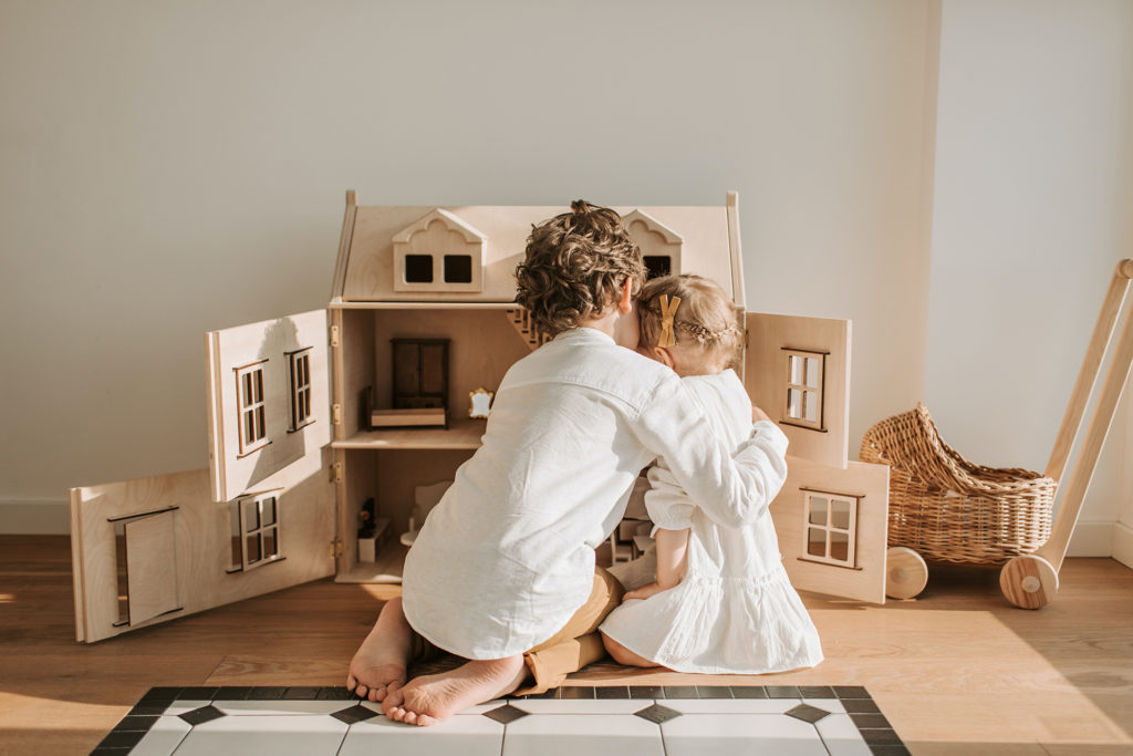 two children hugging in front of playhouse